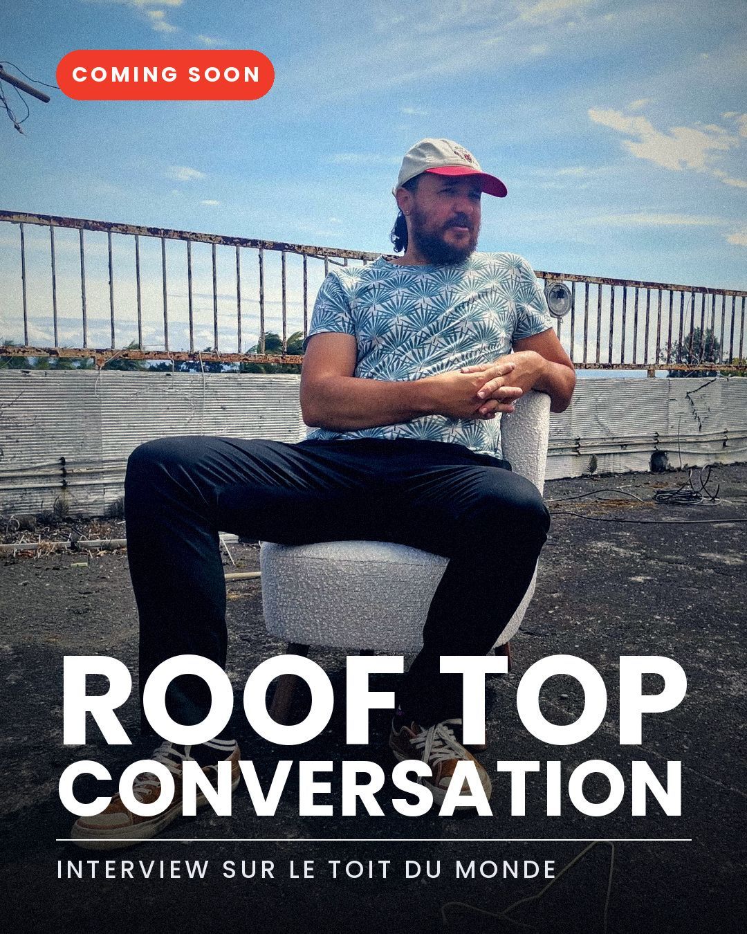Affiche « Roof Top Conversation , interview sur le toit du monde » : un homme en casquette assis dans un fauteuil sur un toit