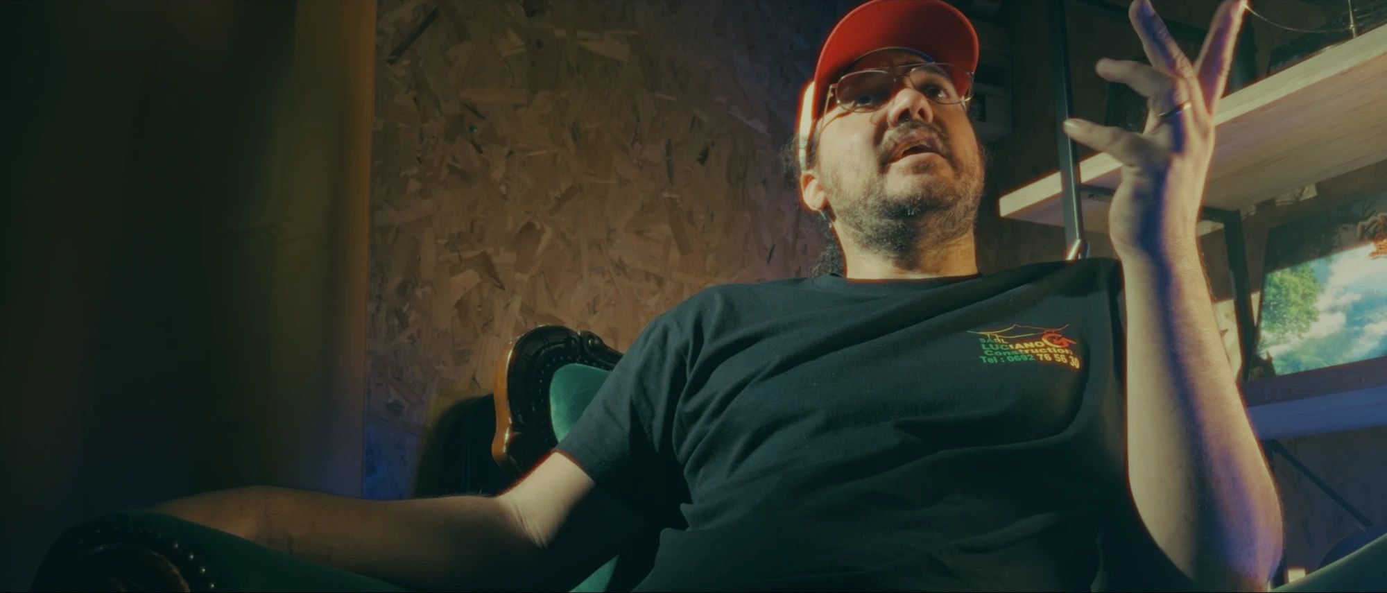 Sébastien Huet, casquette rouge, parle en interview, assis dans un fauteuil du studio