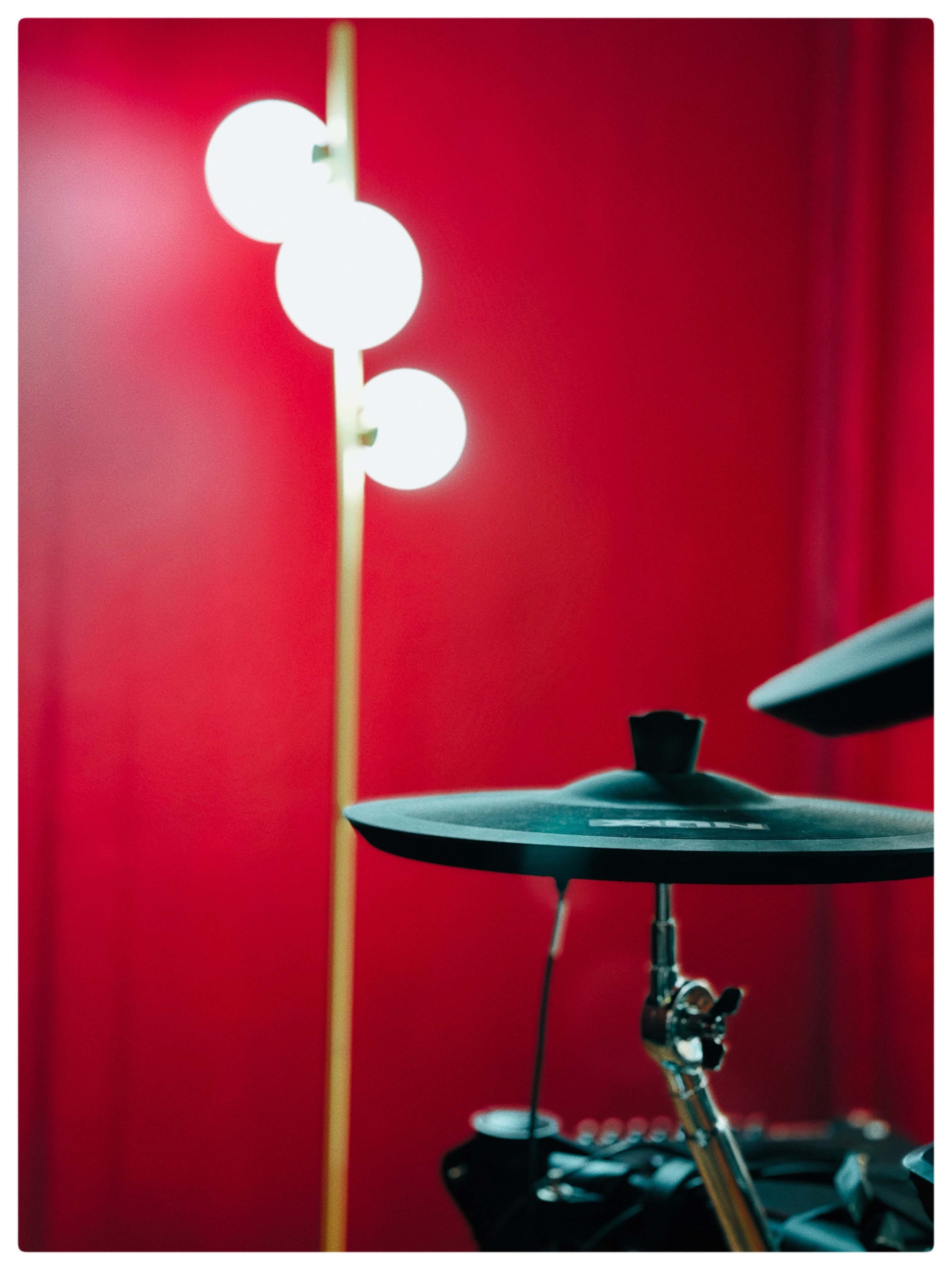 Une cymbale et une lampe à globes devant le mur rouge de la salle